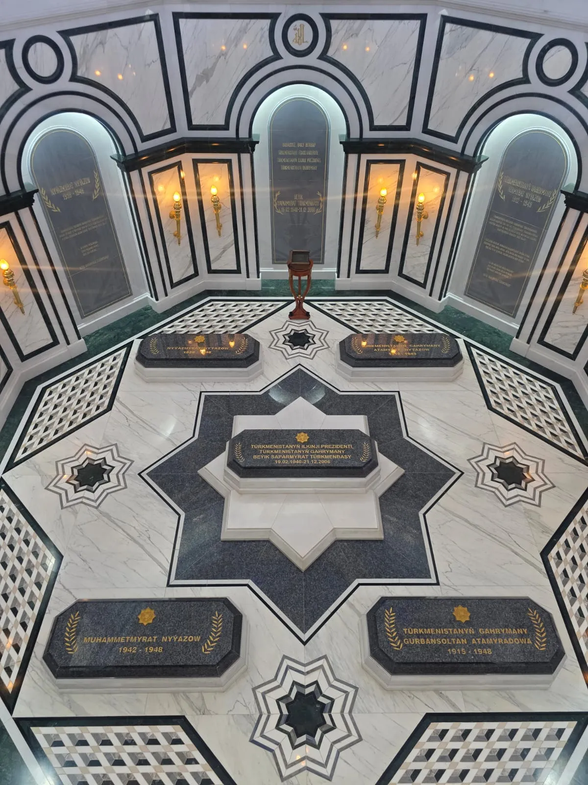 Interior view of the first President of Turkmenistan's family mausoleum in Kipchak, featuring marble floors with eight-pointed stars and stone sarcophagi.