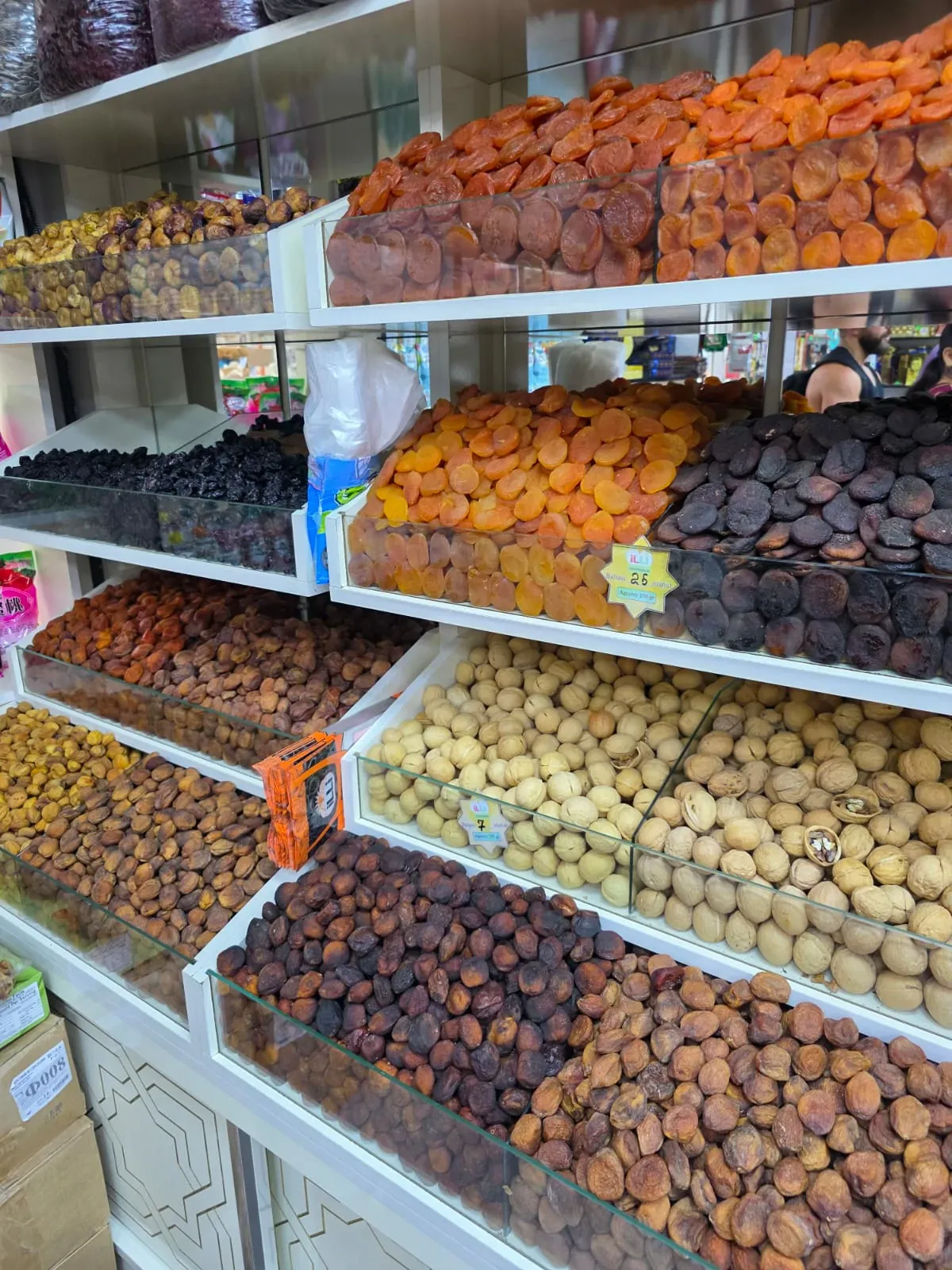 Glass display cases with a large selection of apricots, raisins, figs, and walnuts at a bazaar in Turkmenistan