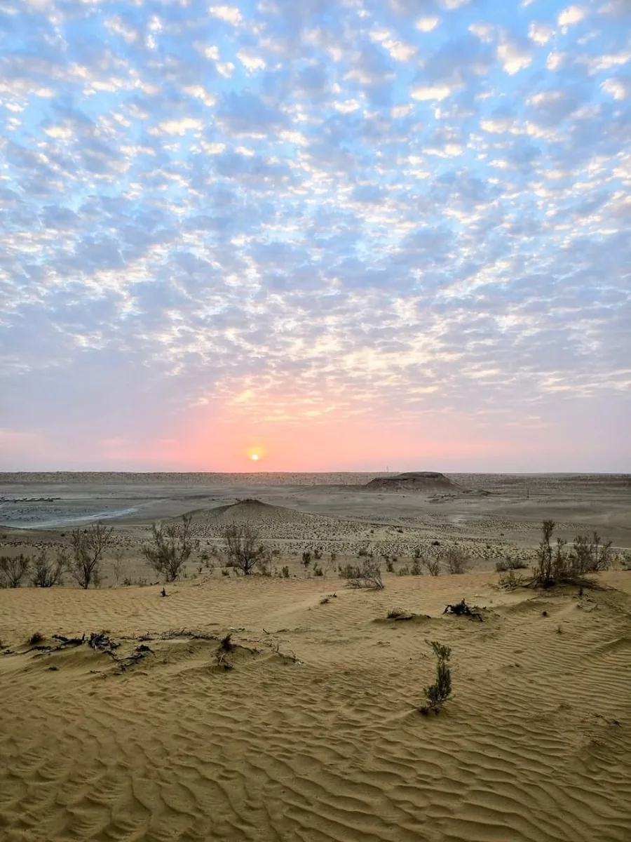 Sunrise over the Karakum Desert in Turkmenistan with sand dunes and a wide cloudy sky