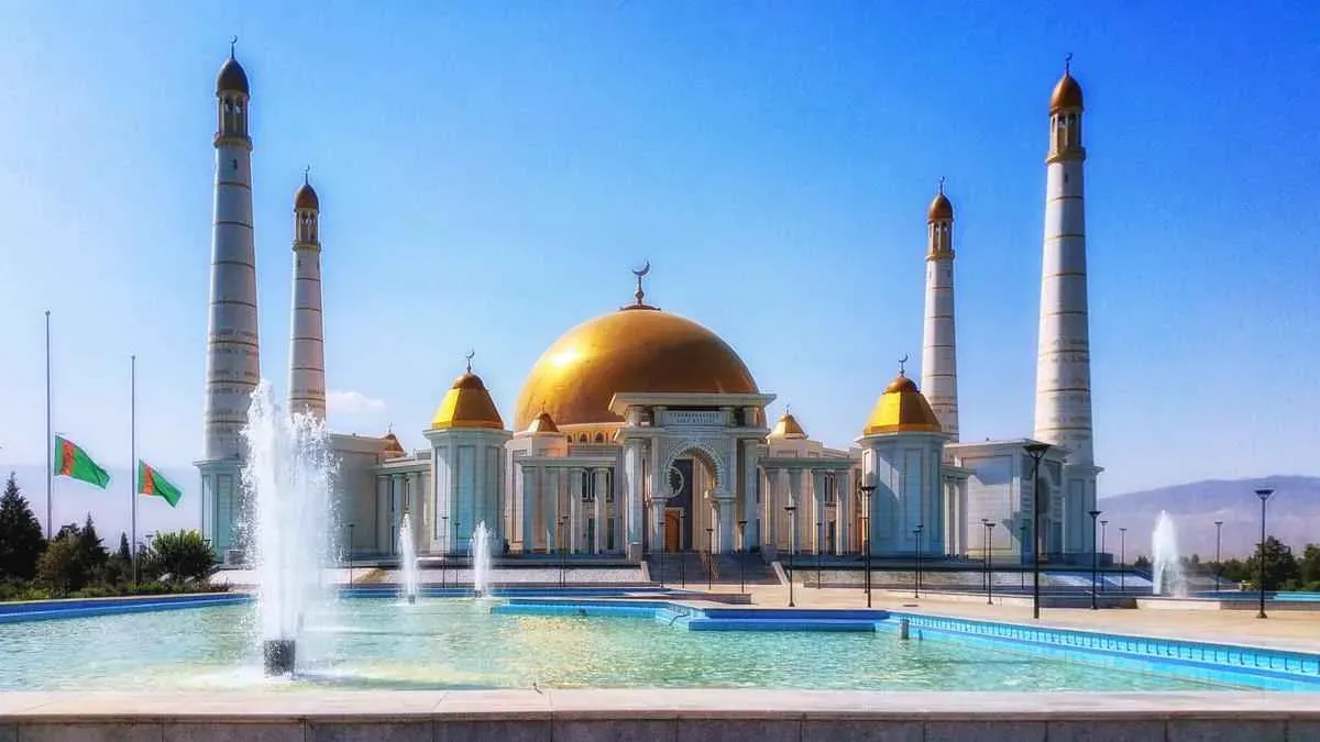 Majestic Turkmenbashi Ruhy Mosque made of white marble with golden domes and tall minarets, fountains spouting in front of the mosque, Ashgabat, Turkmenistan